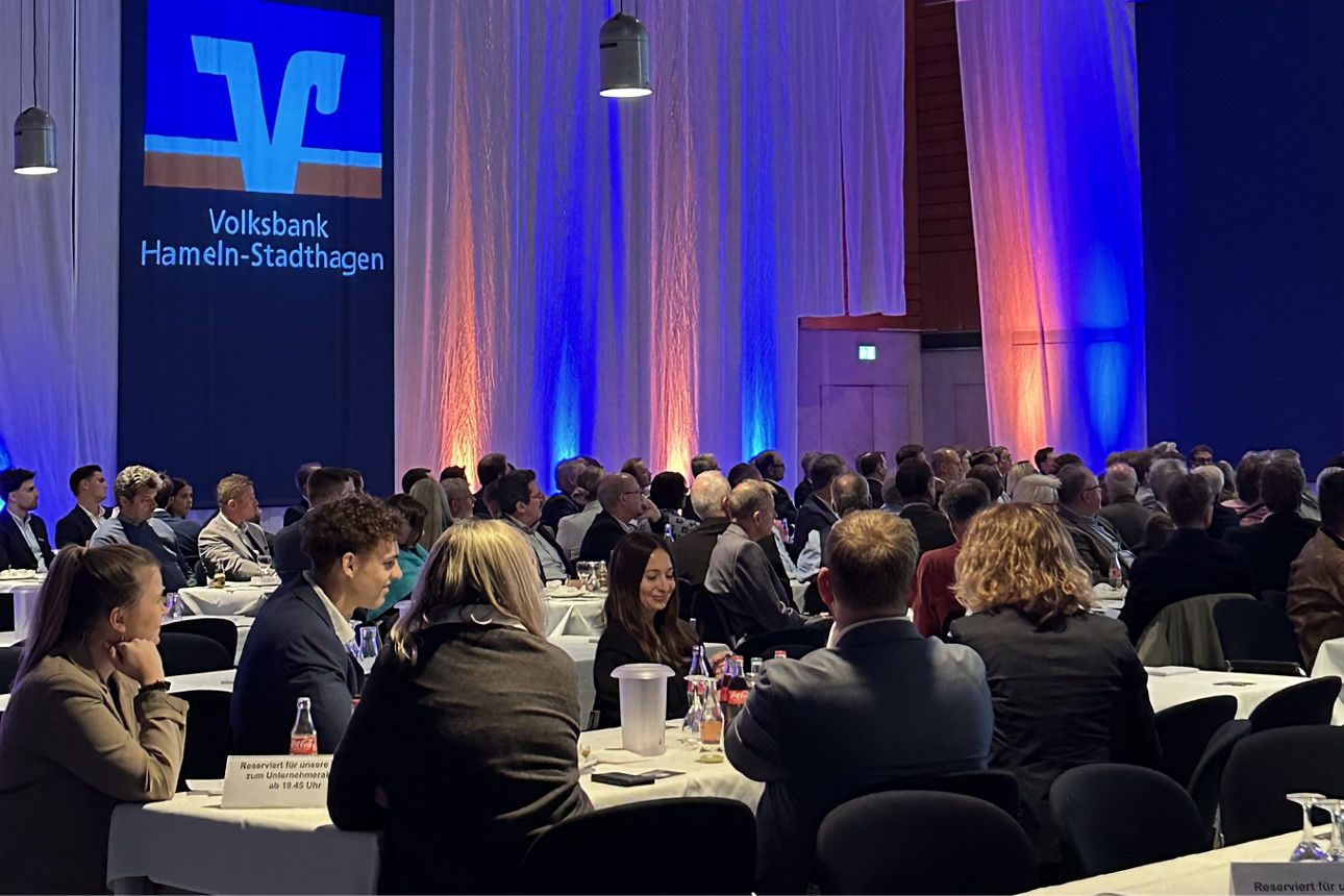 Mehrere Personen sitzen dicht nebeneinander im Publikum einer Veranstaltung