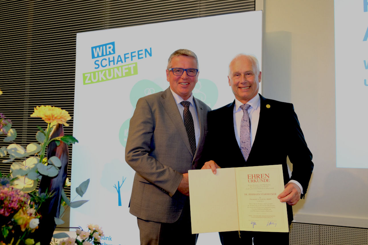 Zwei Personen. Eine Person hält eine Urkunde in der Hand