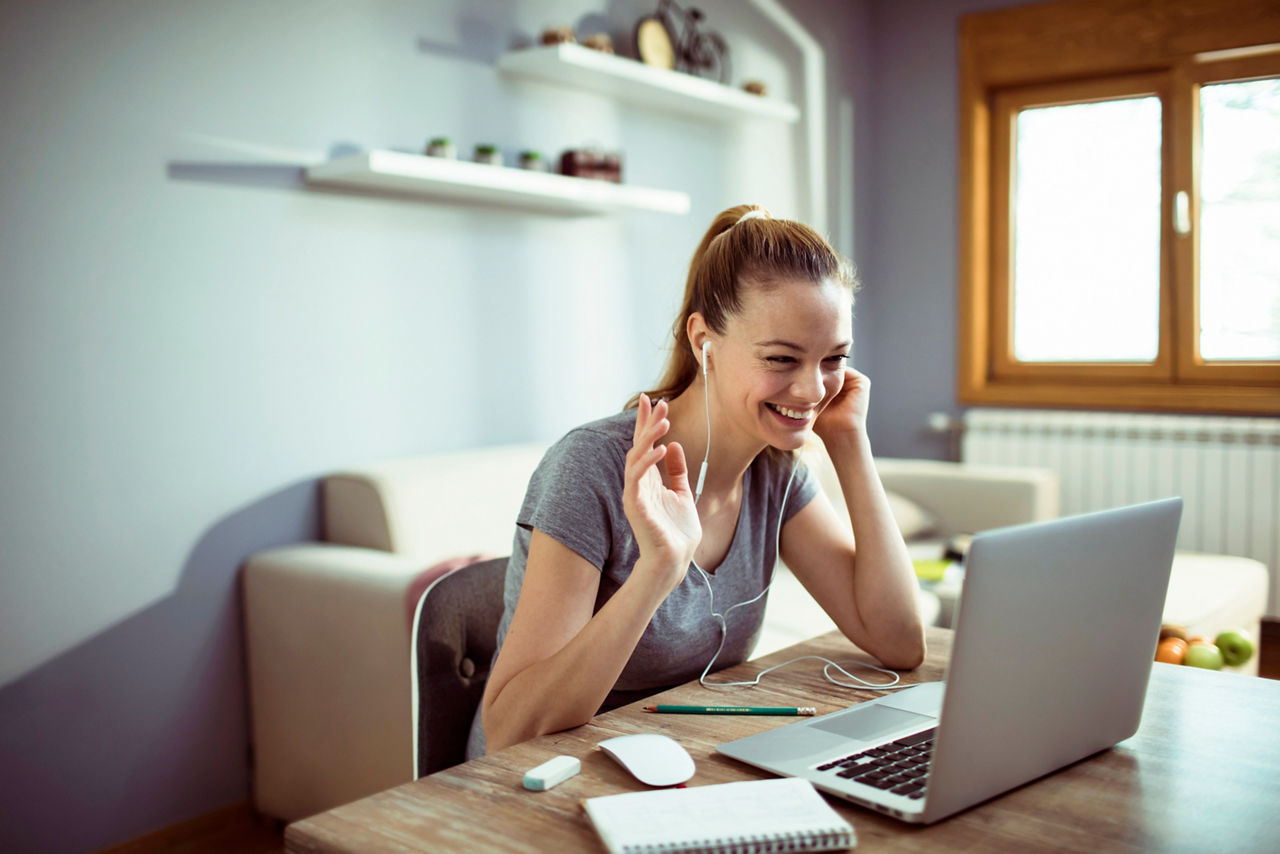 Nahaufnahme einer jungen Frau, die zu Hause einen Laptop für Videokonferenzen benutzt.