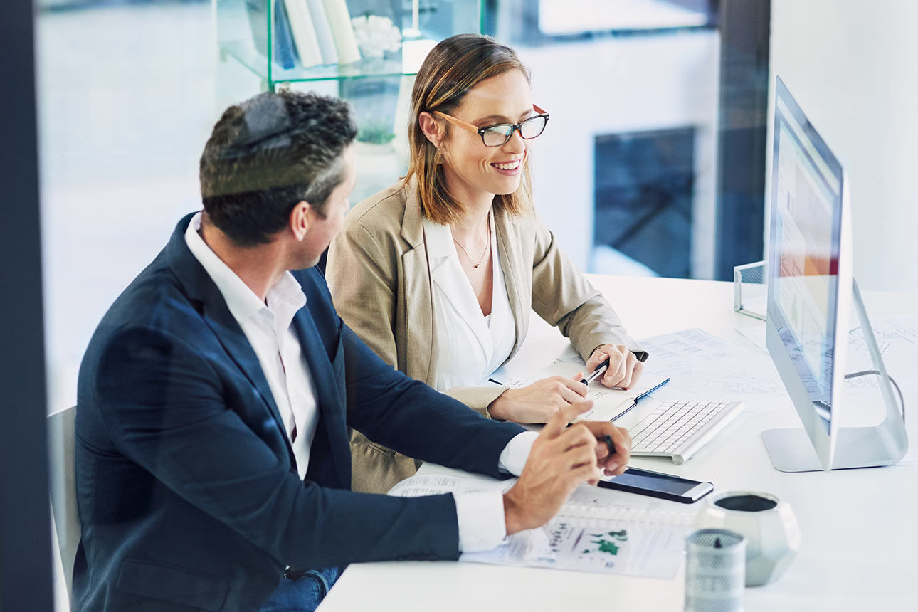 Ein Mann und eine Frau sitzen im Büro gemeinsam vor einen Bildschirm