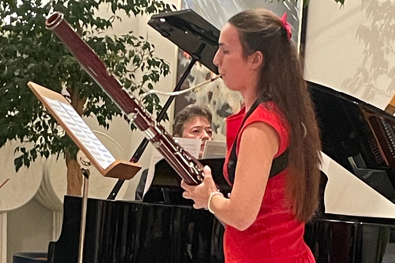 Eine Frau neben einem Flügel, wärend sie ein Instrument spielt. 