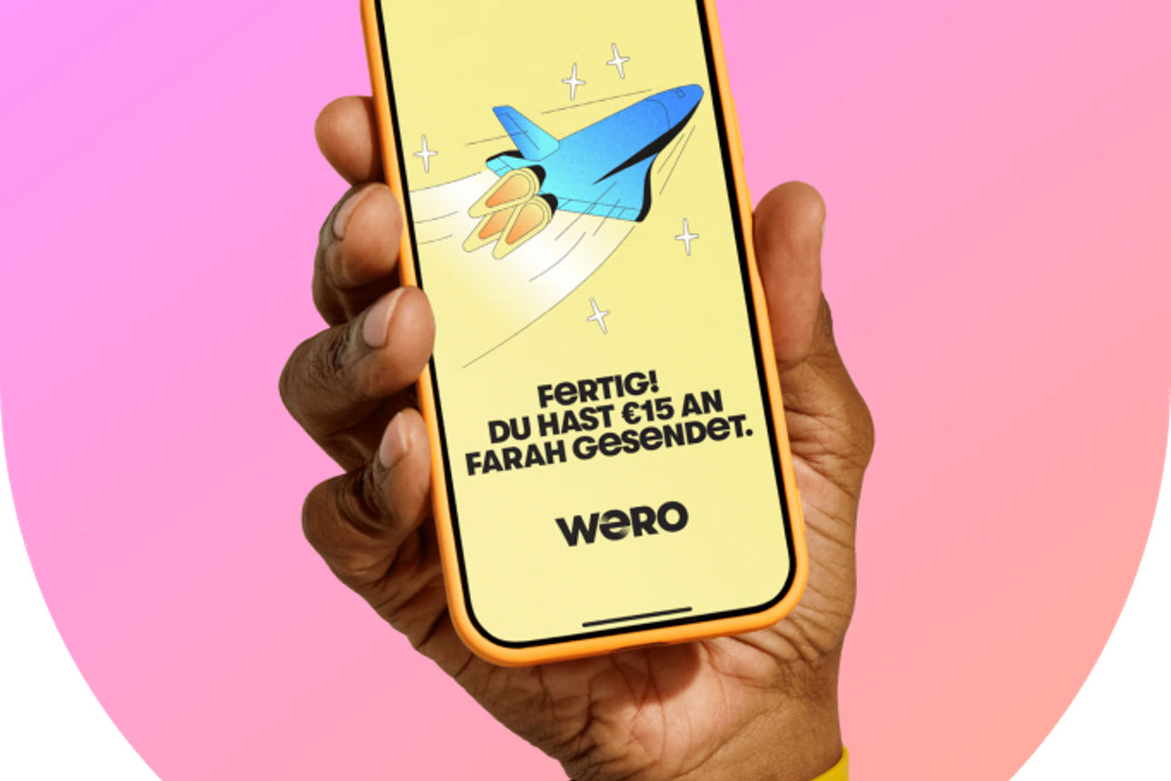 Hand mit einem Smartphone und einer Wero "Geld versendet" Bestätigung