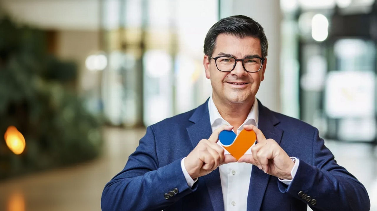 Vorstandsmitglied Jürgen Neutgens hält ein baluorangefarbiges Herz in den Händen