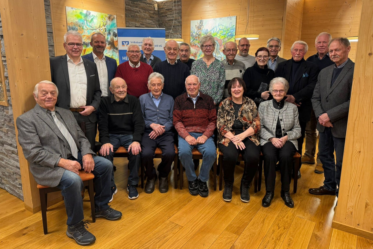 Eine junge Frau steht mit Farbflecken auf der Kleidung und einem Pinsel zwischen Mund und Nase geklemmt in einem Atelier