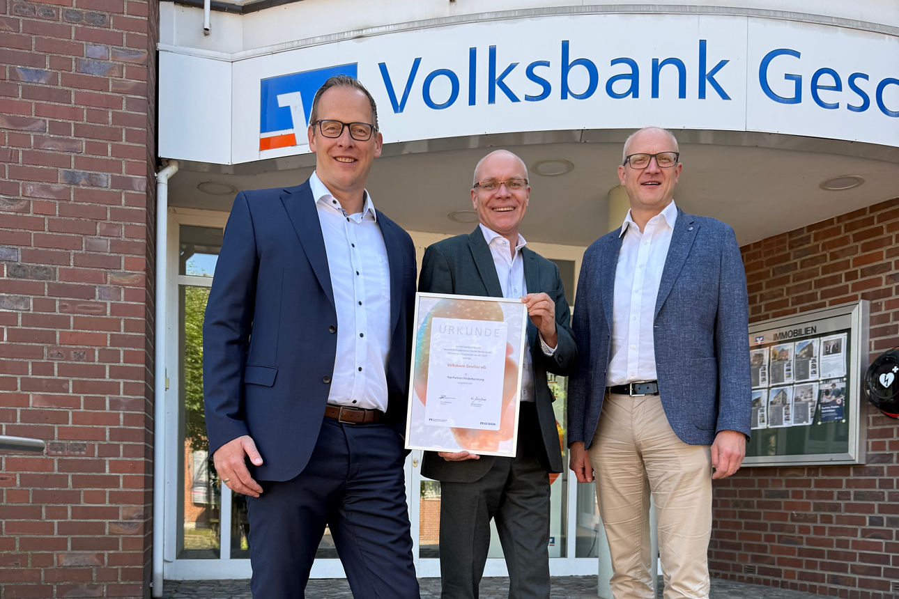 Drei Männer in Anzügen, der mittlere hält das Zertifikat „Top Partner Förderberatung“ in der Hand.