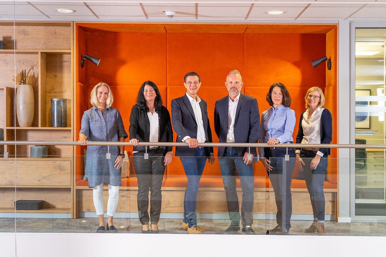 Team der VB Immobilien GmbH vor einer organgen Wand
