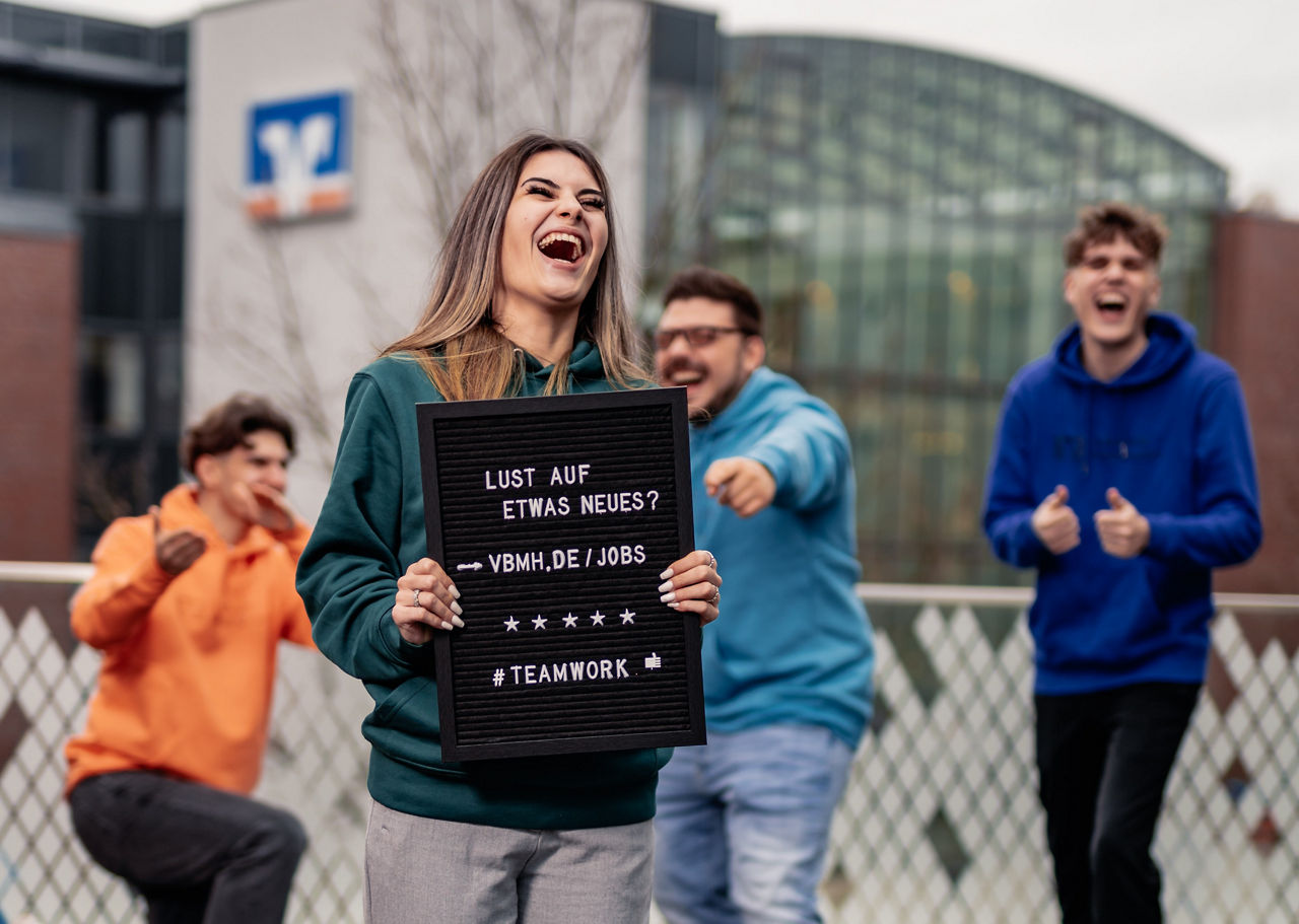 Mitarbeiterin der Volksbank Mittelhessen hält eine Schild zum Bewerben hoch