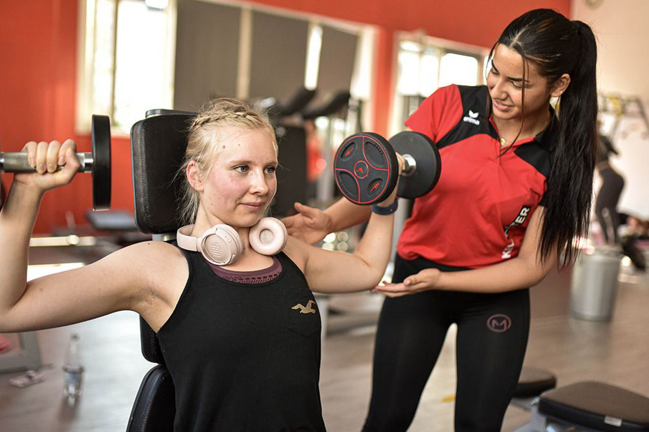 Eine Frau betraut eine weitere Frau beim Probetraining im Fitnesscenter