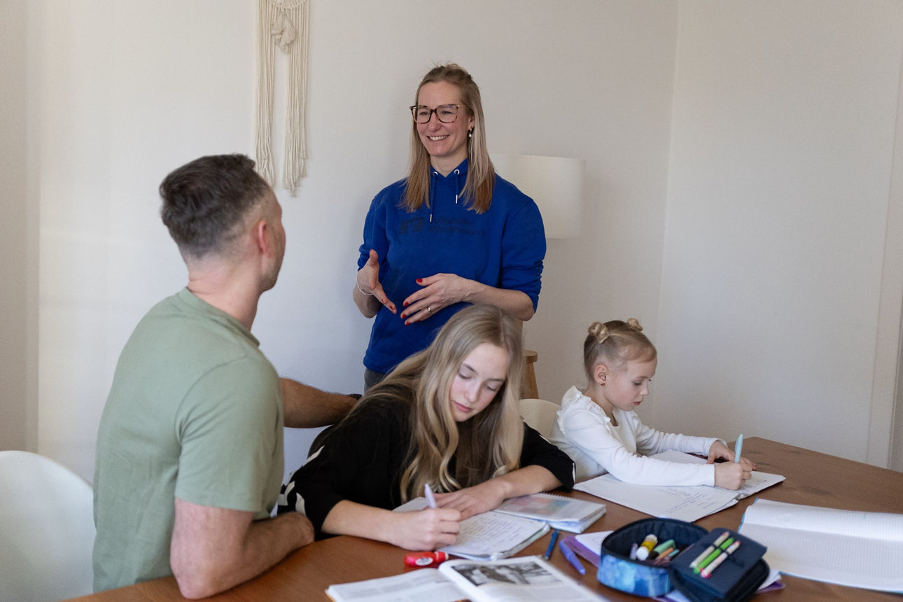 Mitarbeiter hilft Kindern bei den Hausaufgaben