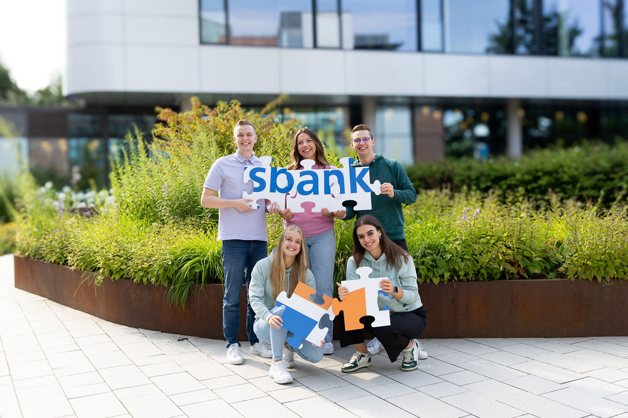 Gruppe von Personen, halten das Volksbanklogo als Puzzel in der Hand