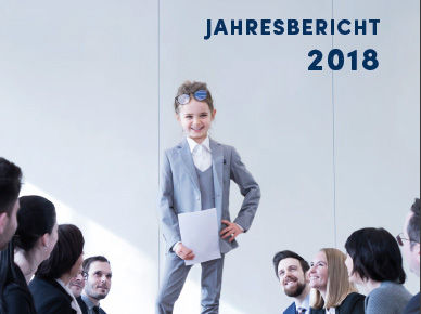 Kind im Anzug steht auf dem Tisch. Drum herum Erwachsene Personen