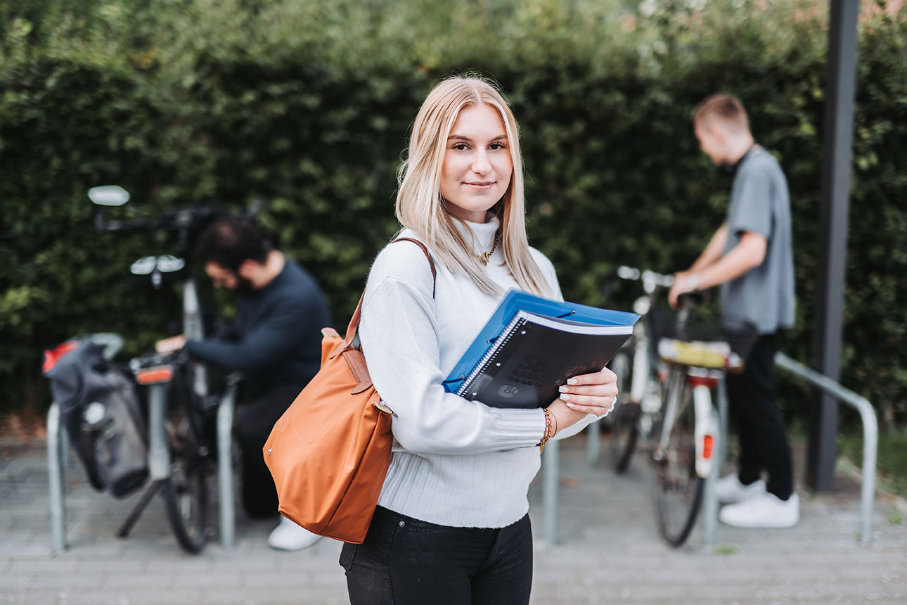 Junge Frau mit Block guckt in die Kamera
