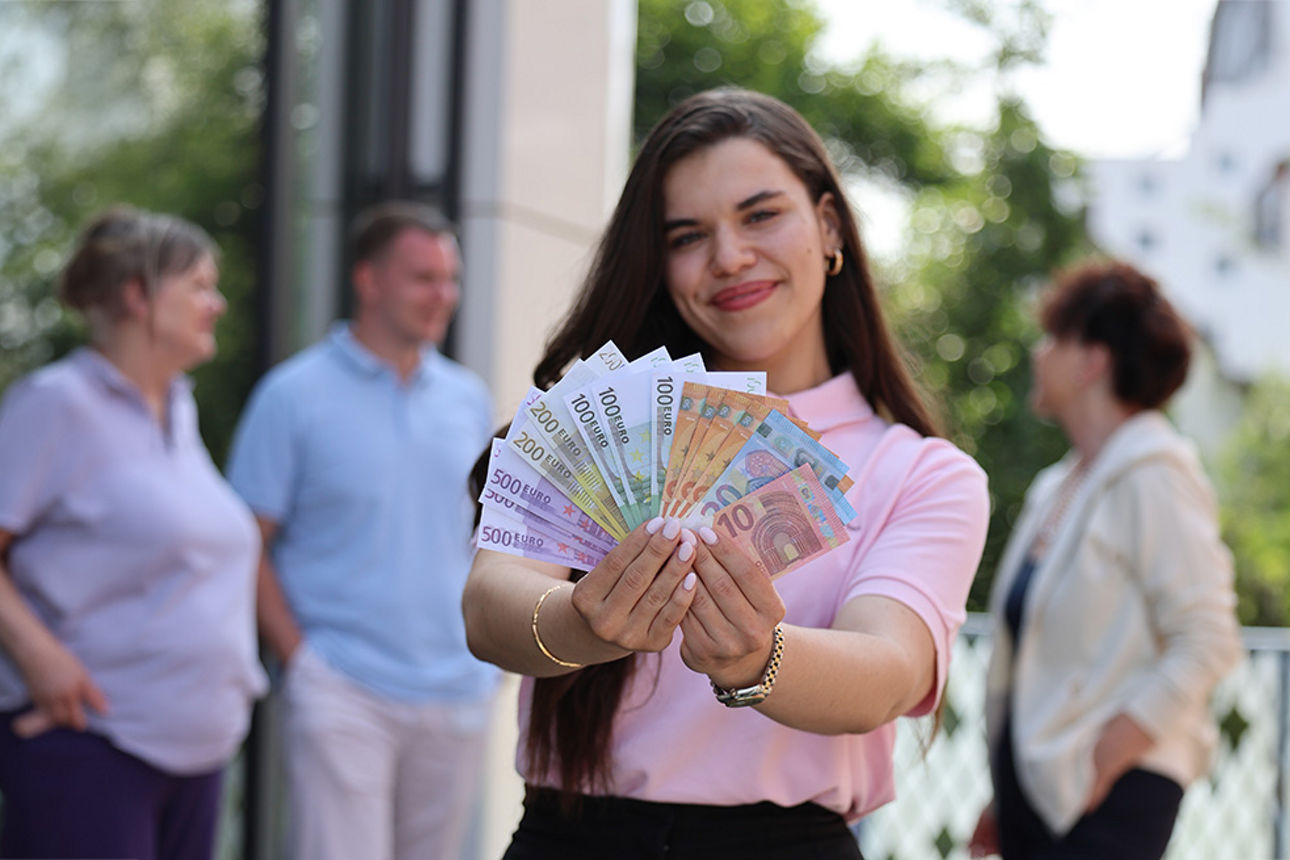 Junge Frau hält viele unterschiedliche Geldscheine in der Hand