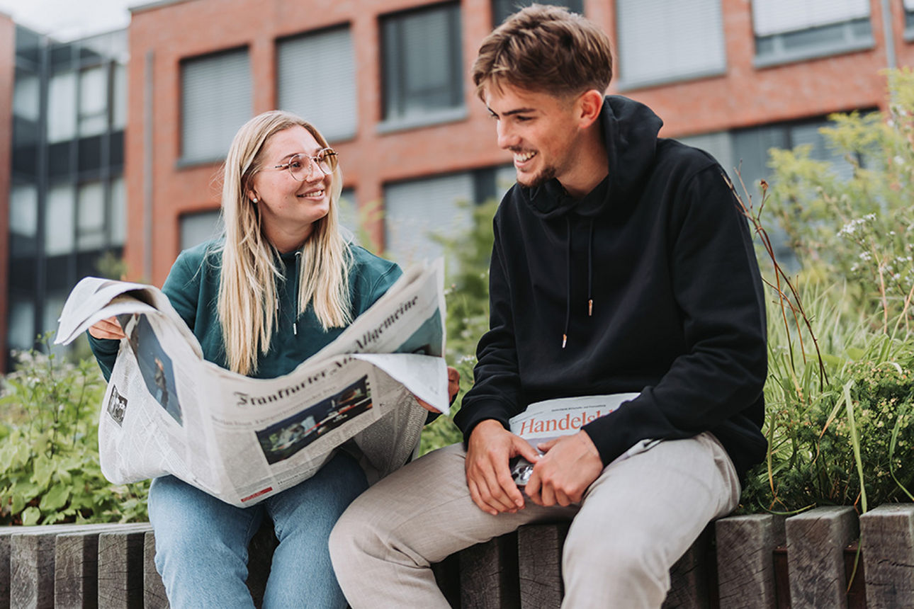 Zwei Menschen sitzen und lesen Zeitung