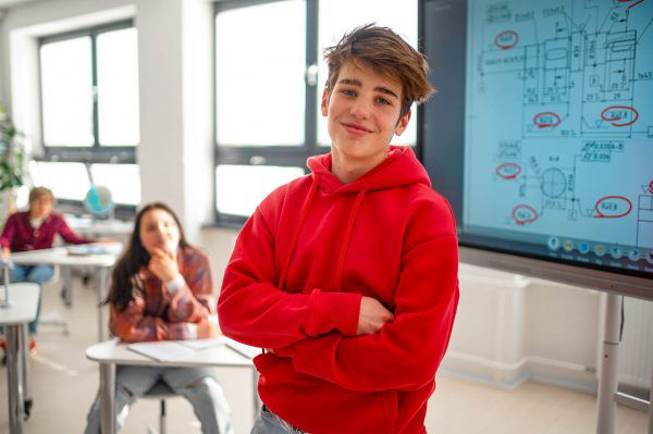 Junge steht in der Schule vor einem digitalen Whiteboard