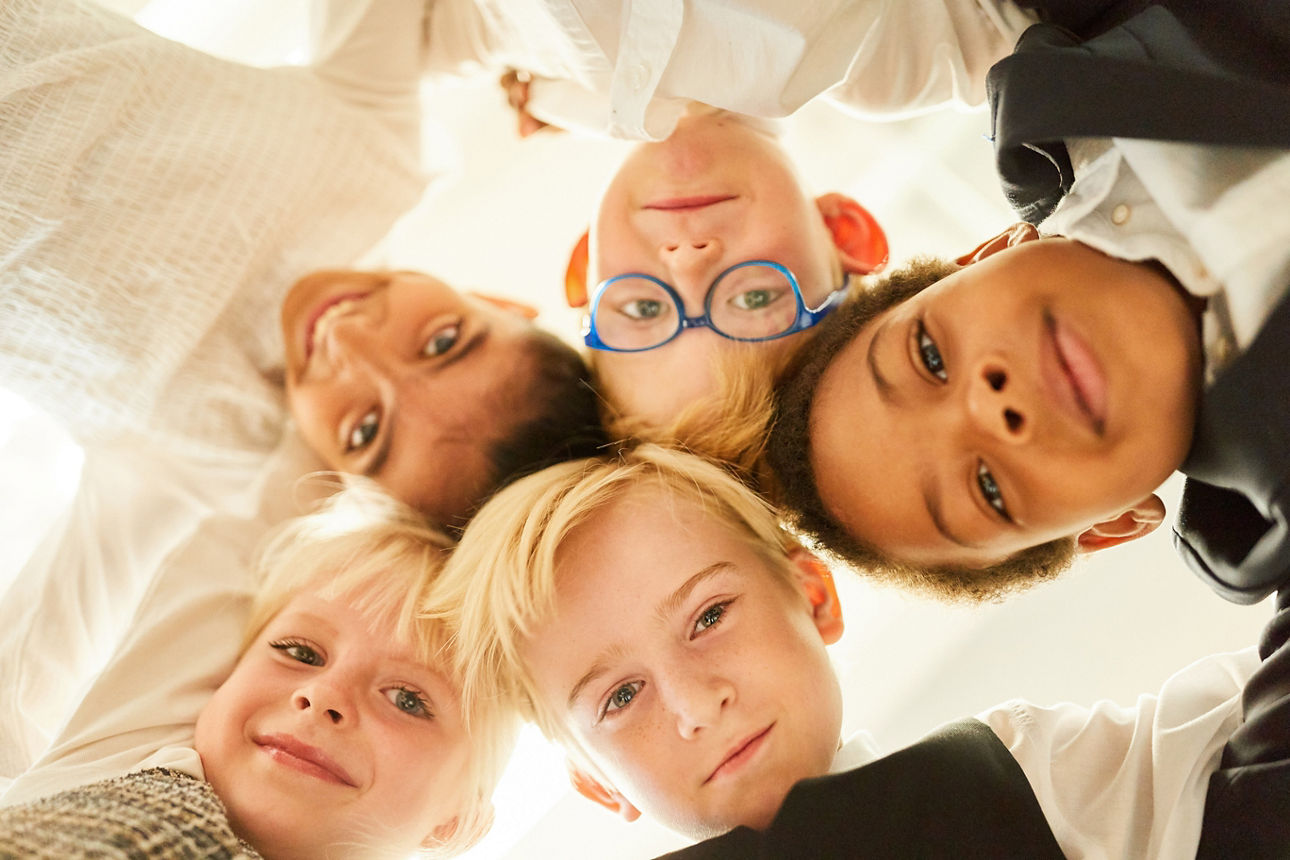 Multikulturelle Gruppe Kinder in Business Outfits als glückliche Freunde im Kreis