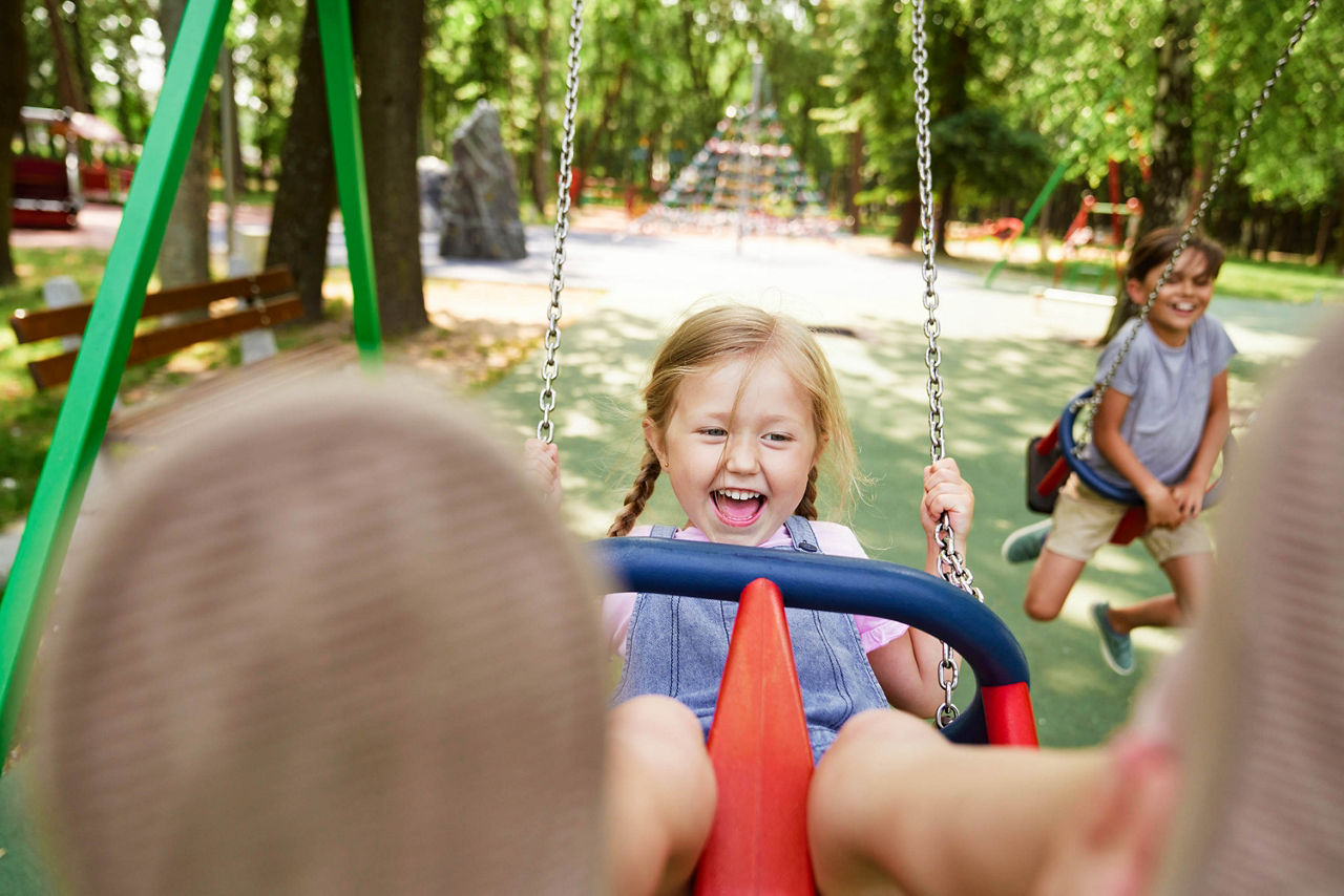 Kleines Mädchen schauckelt auf dem Spielplatz