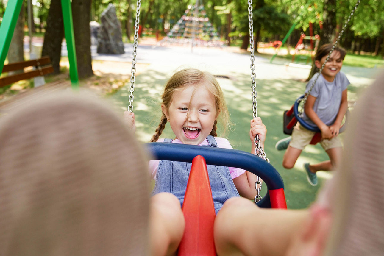 Kleines Mädchen schauckelt auf dem Spielplatz
