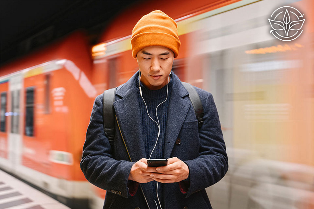 Mann in einer U-Bahn-Station, der auf sein Smartphone schaut