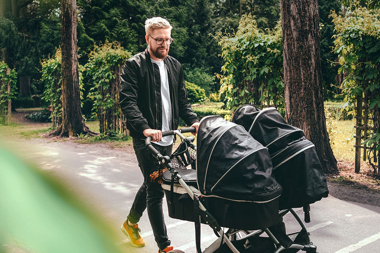Mann mit Kinderwagen für Zwillinge