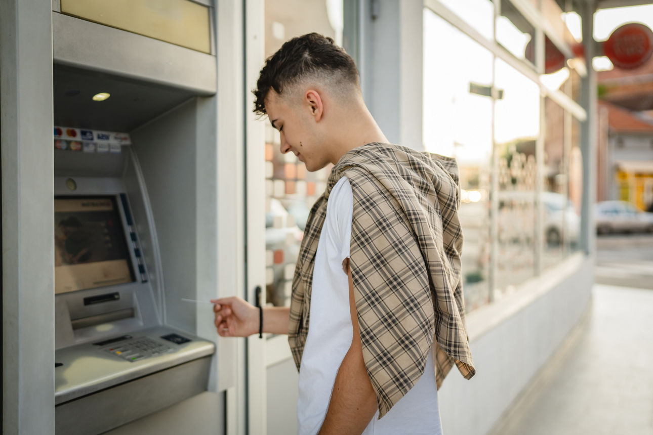 Student hebt mit seiner Kreditkarte Geld an einem Automaten im Ausland ab