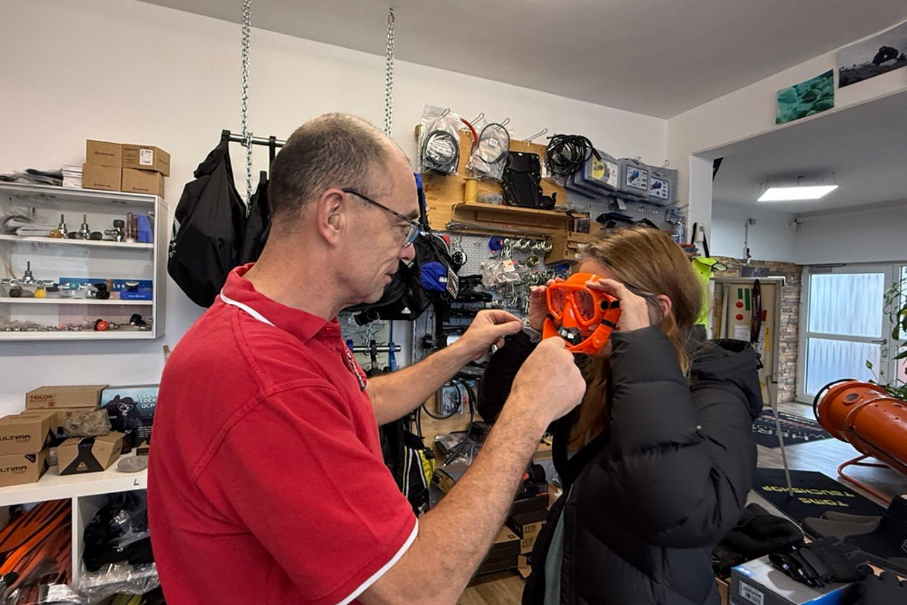 Fotografie von dem Ladenbesitzer bei der Taucherbrillenabprobe für eine Kundin im Laden