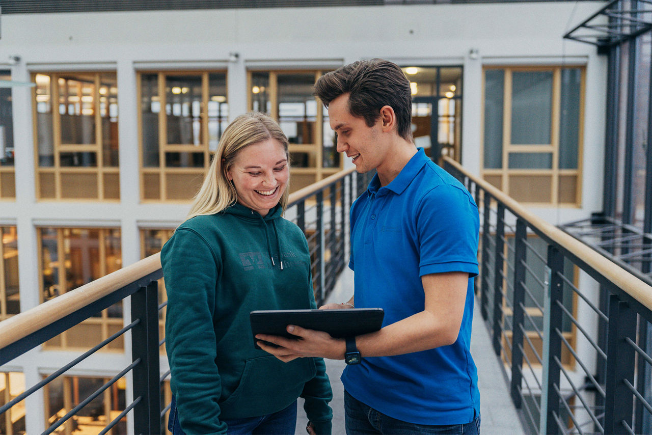 Zwei Kollegen schauen glücklich auf ein Ipad