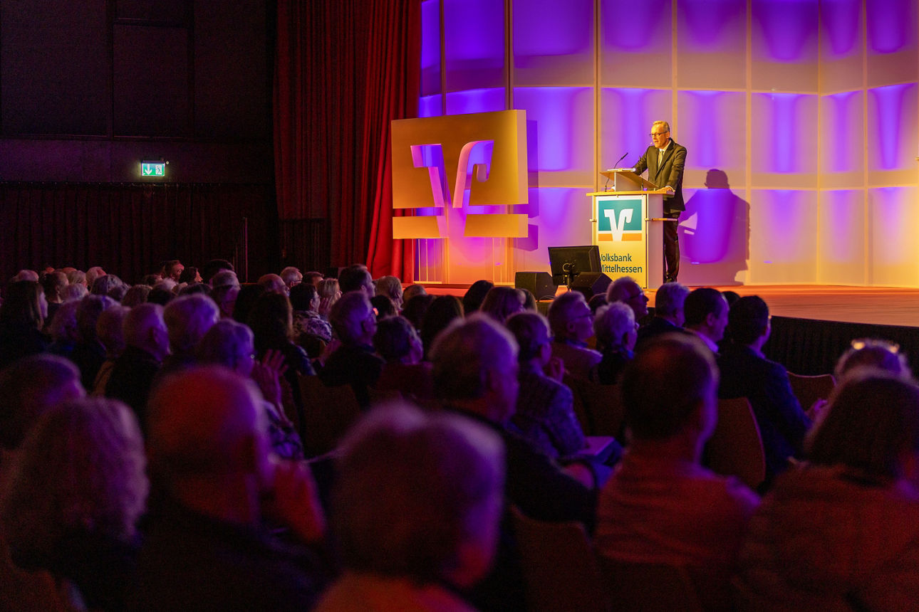 Gruppe von Menschen schauen Dr. Peter Hanker auf der Bühne an