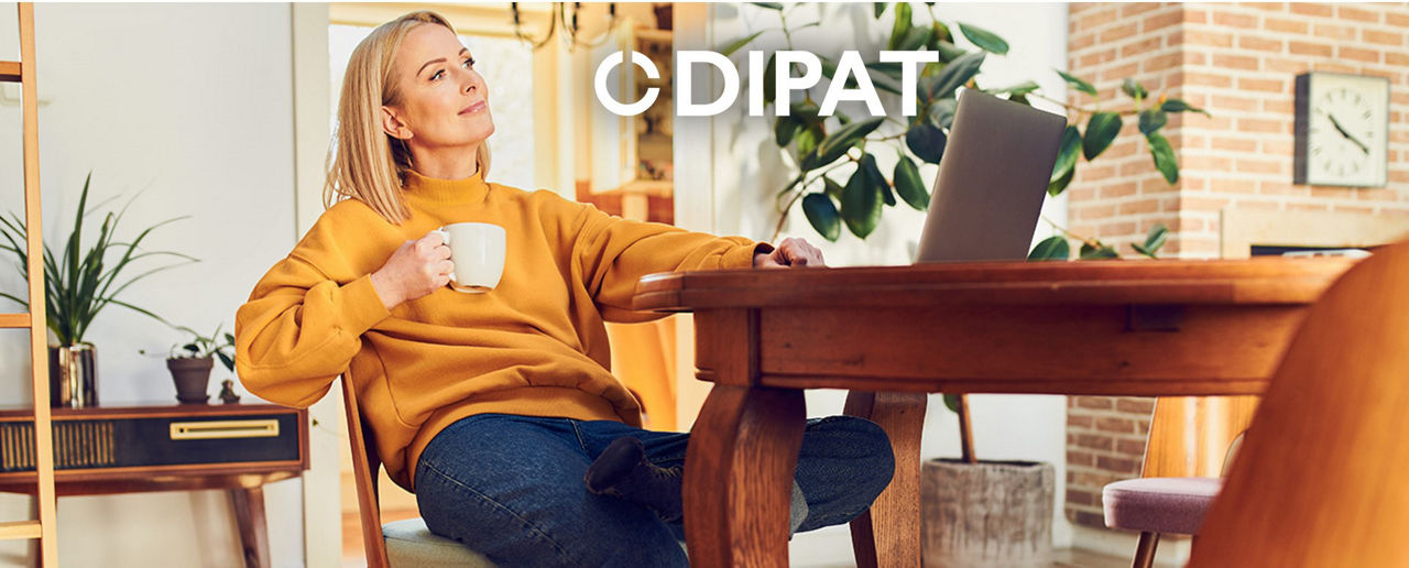 Frau sitzt vorm Laptop mit einer Tasse Kaffee in der Hand