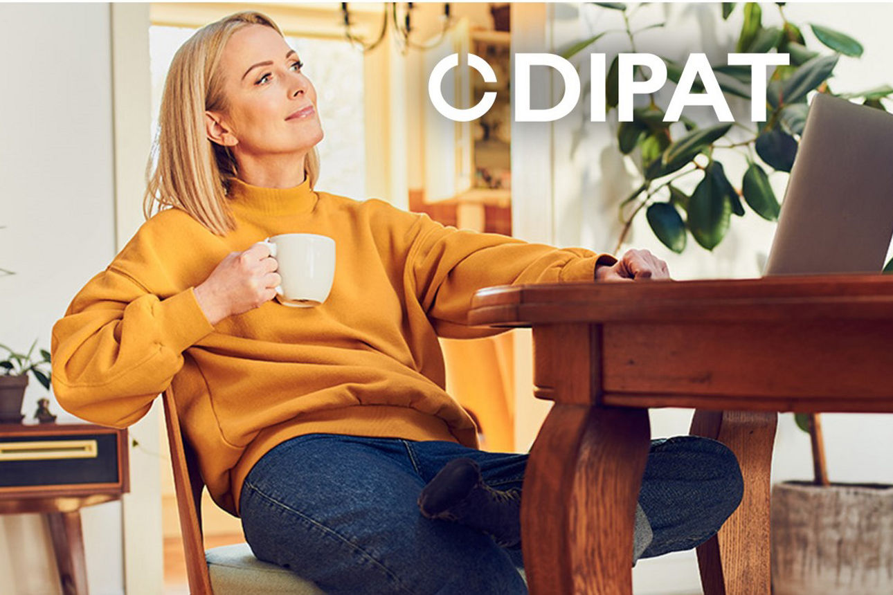 Frau sitzt vorm Laptop mit einer Tasse Kaffee in der Hand