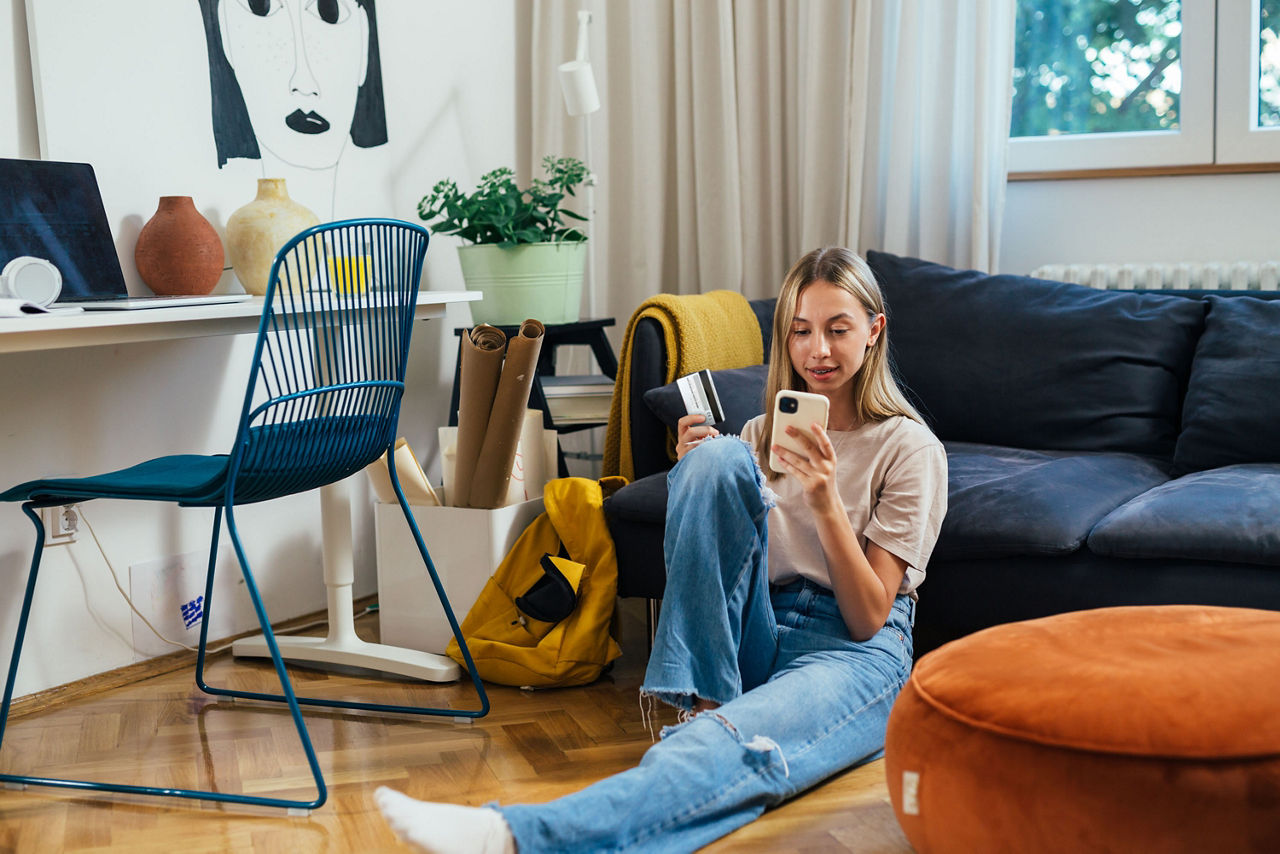 Jugendliche shoppt über das Handy im Wohnzimmer