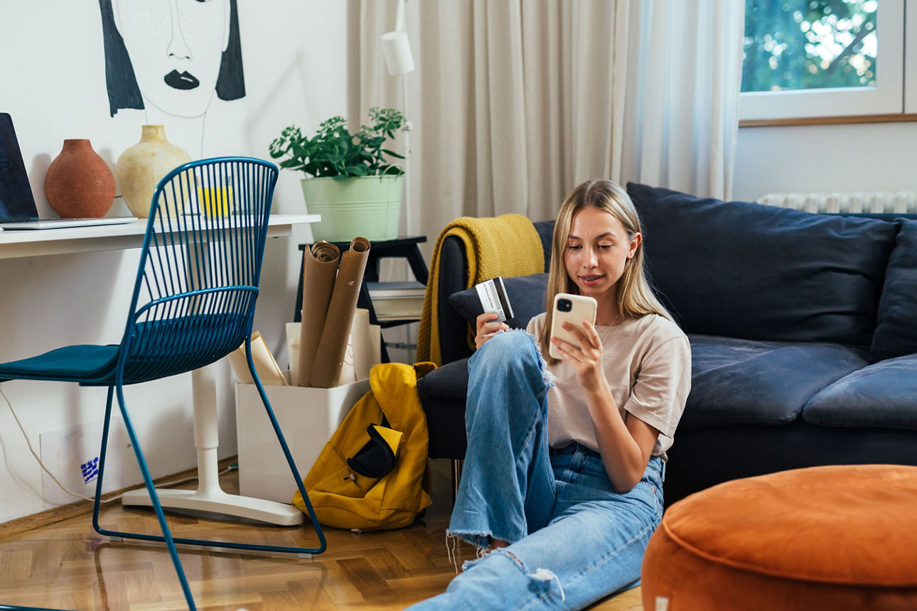 Jugendliche shoppt über das Handy im Wohnzimmer