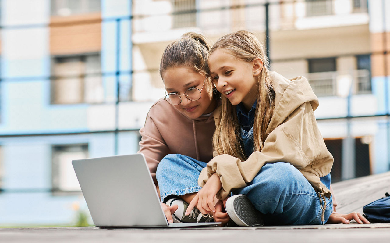 Zwei Schulmädchen schauen auf einen Laptop