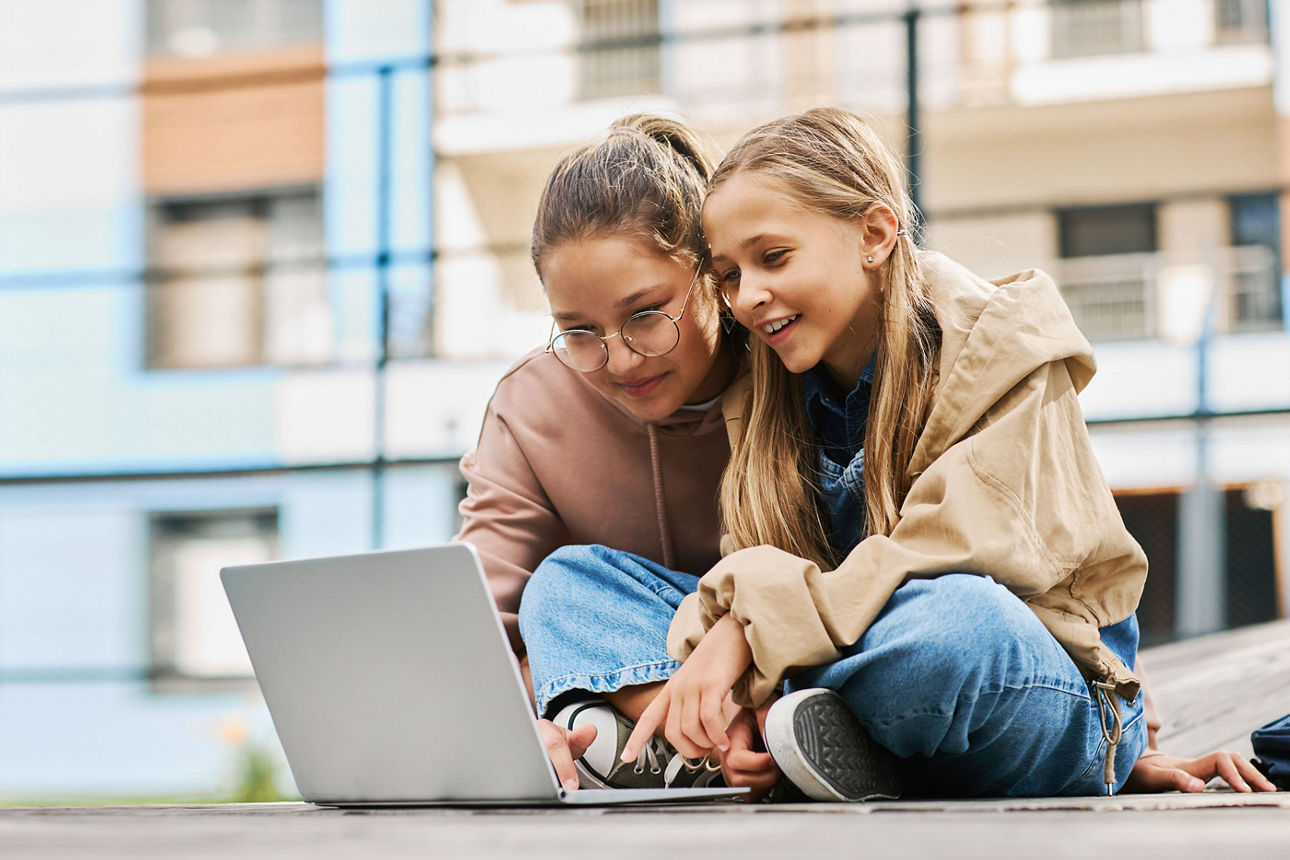 Zwei Schulmädchen schauen auf einen Laptop
