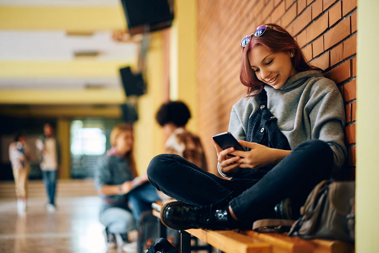 Jugendliche Teenagerin sitzt in der Schule am Handy