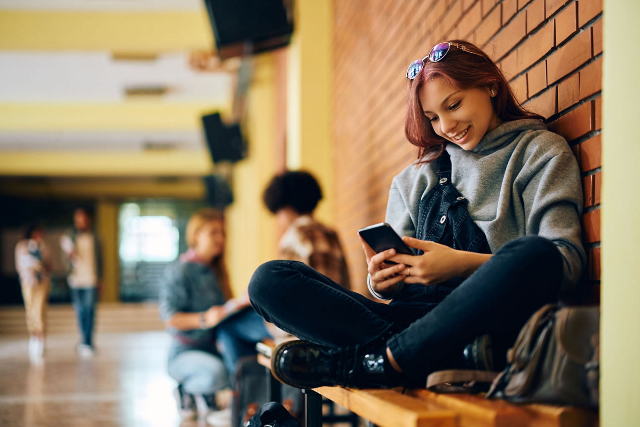 Jugendliche Teenagerin sitzt in der Schule am Handy