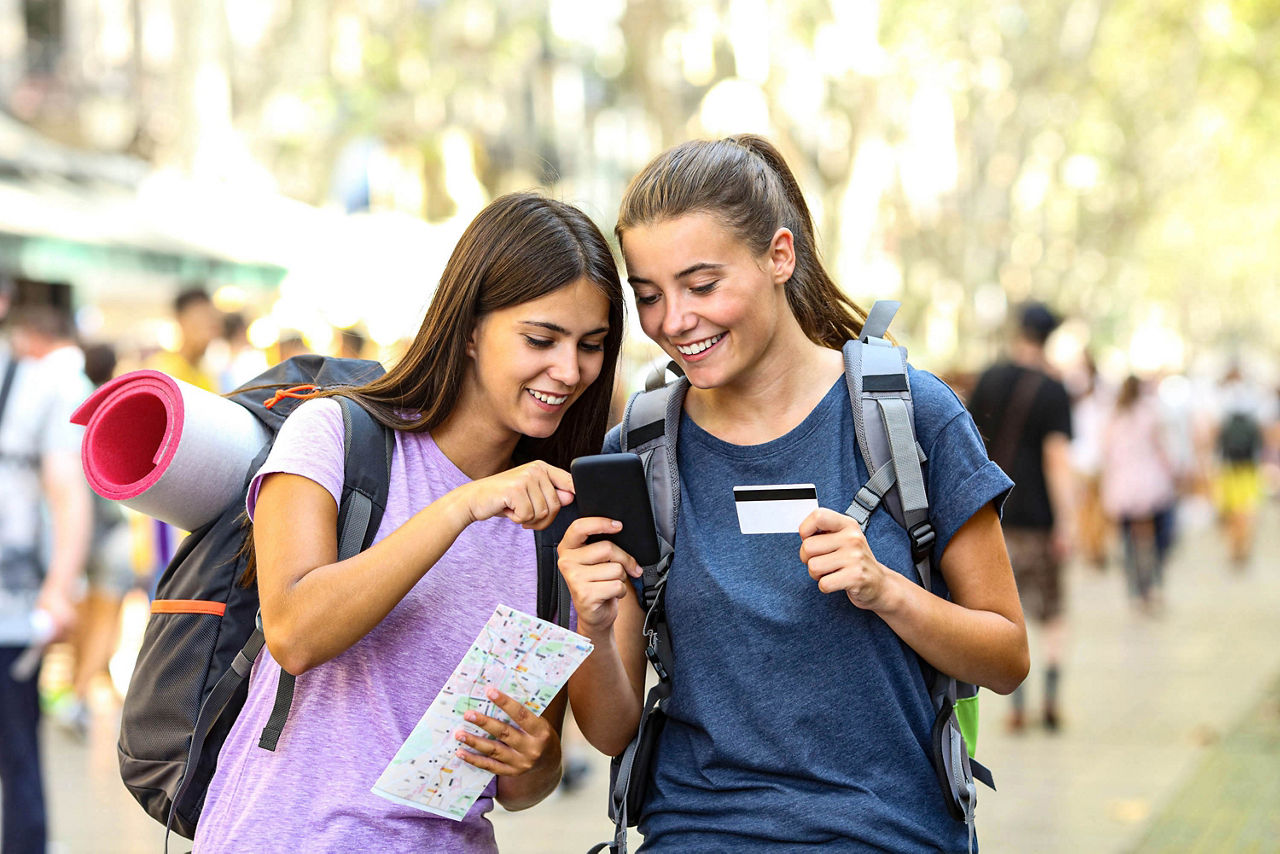 Zwei glückliche Rucksacktouristen, die auf der Straße Online-Inhalte in einem Smartphone suchen