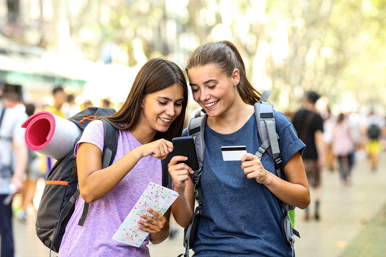 Zwei glückliche Rucksacktouristen, die auf der Straße Online-Inhalte in einem Smartphone suchen