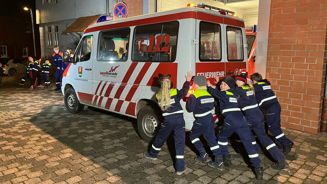 Personen der freiwilligen Feuerwehr schieben das alte Einsatzfahrzeug