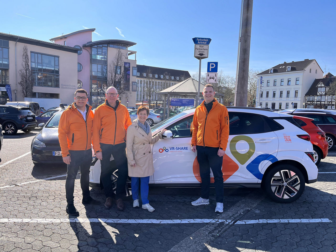 Vier Personen stehen vor dem nachhaltigen Carsharingauto