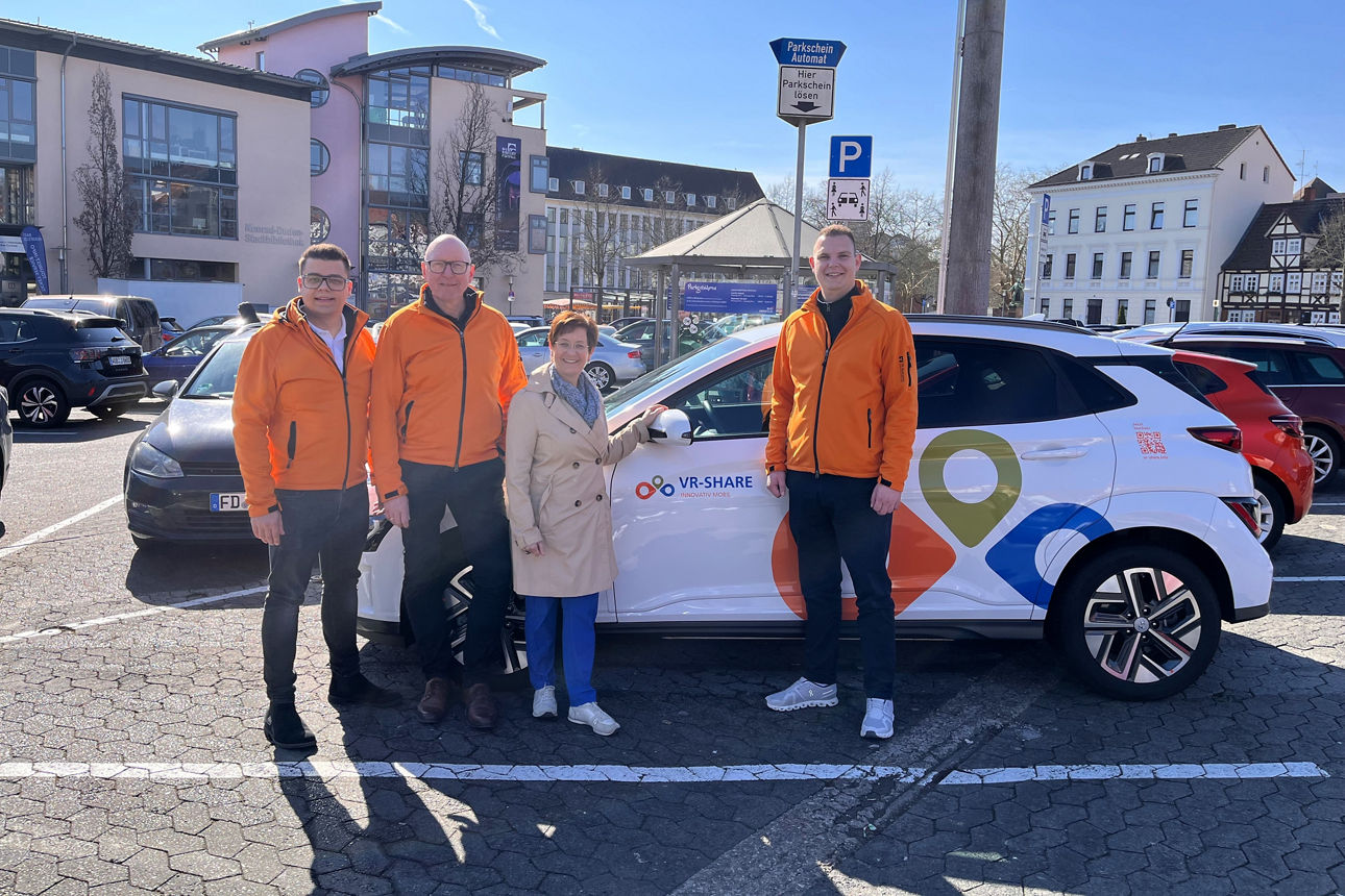 Vier Personen stehen vor dem nachhaltigen Carsharingauto