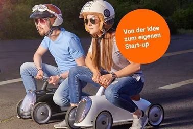Zwei Personne auf einer selbstgebauten Seifenkiste mit Helm