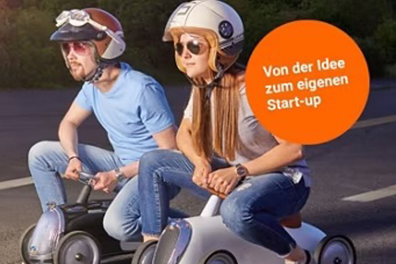 Zwei Personne auf einer selbstgebauten Seifenkiste mit Helm
