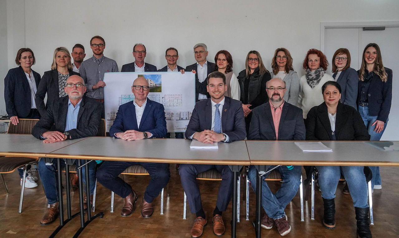 Gruppenfoto mit Grundrissen des neuen Gesundheitszentrums