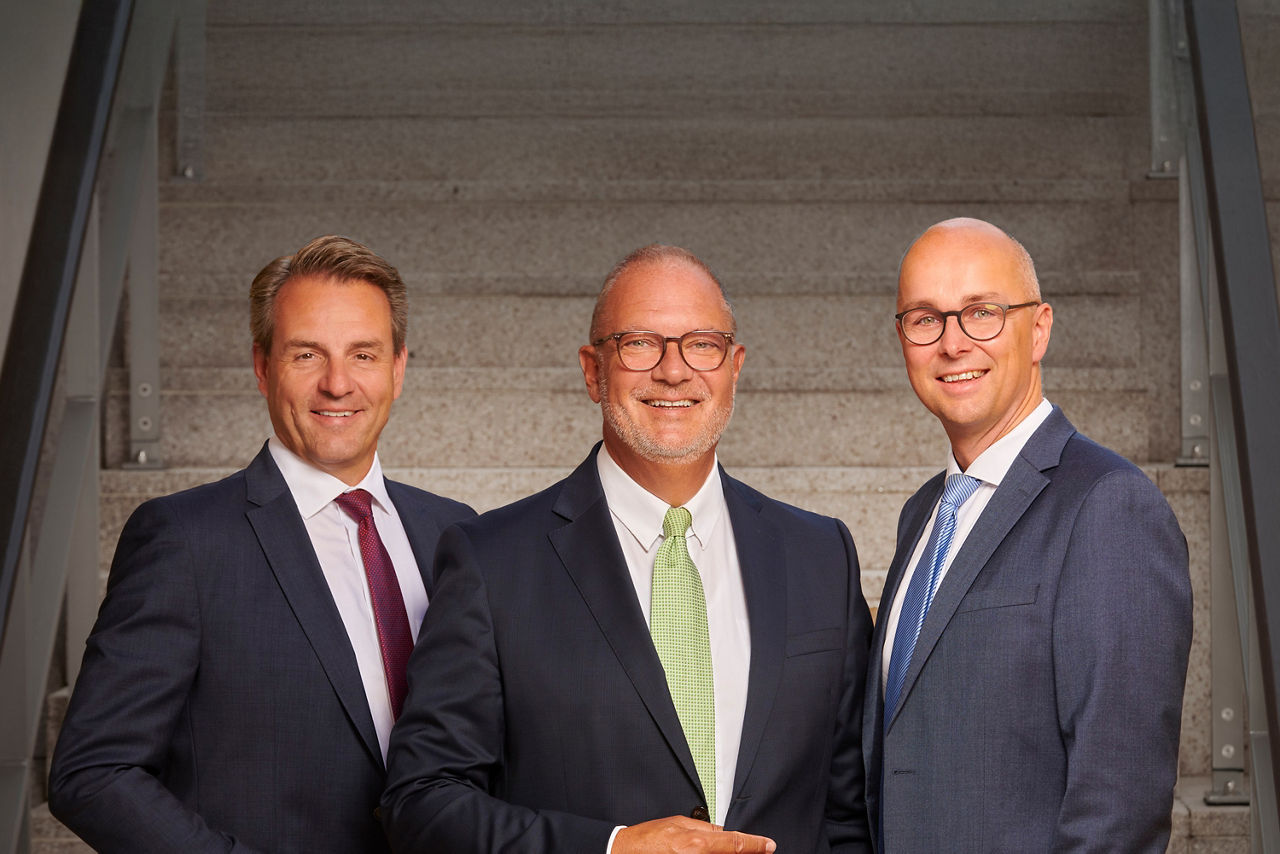 Georg Alder, Holger Franz und Guido Mülder stehen im Anzug nebeneinander