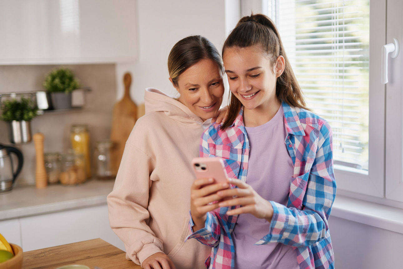 Eine Mutter und eine Tochter schauen gemeinsam auf ein Handy