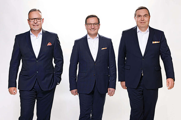 drei Männer in dunkelblauen Anzügen und weißen Hemden