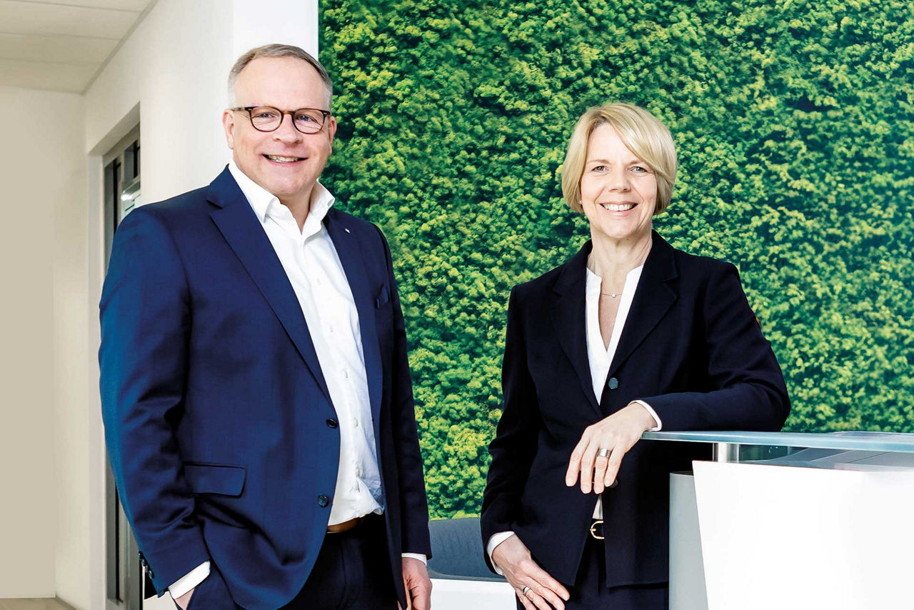 Ein Mann und eine Frau stehen vor einer grünen Wand