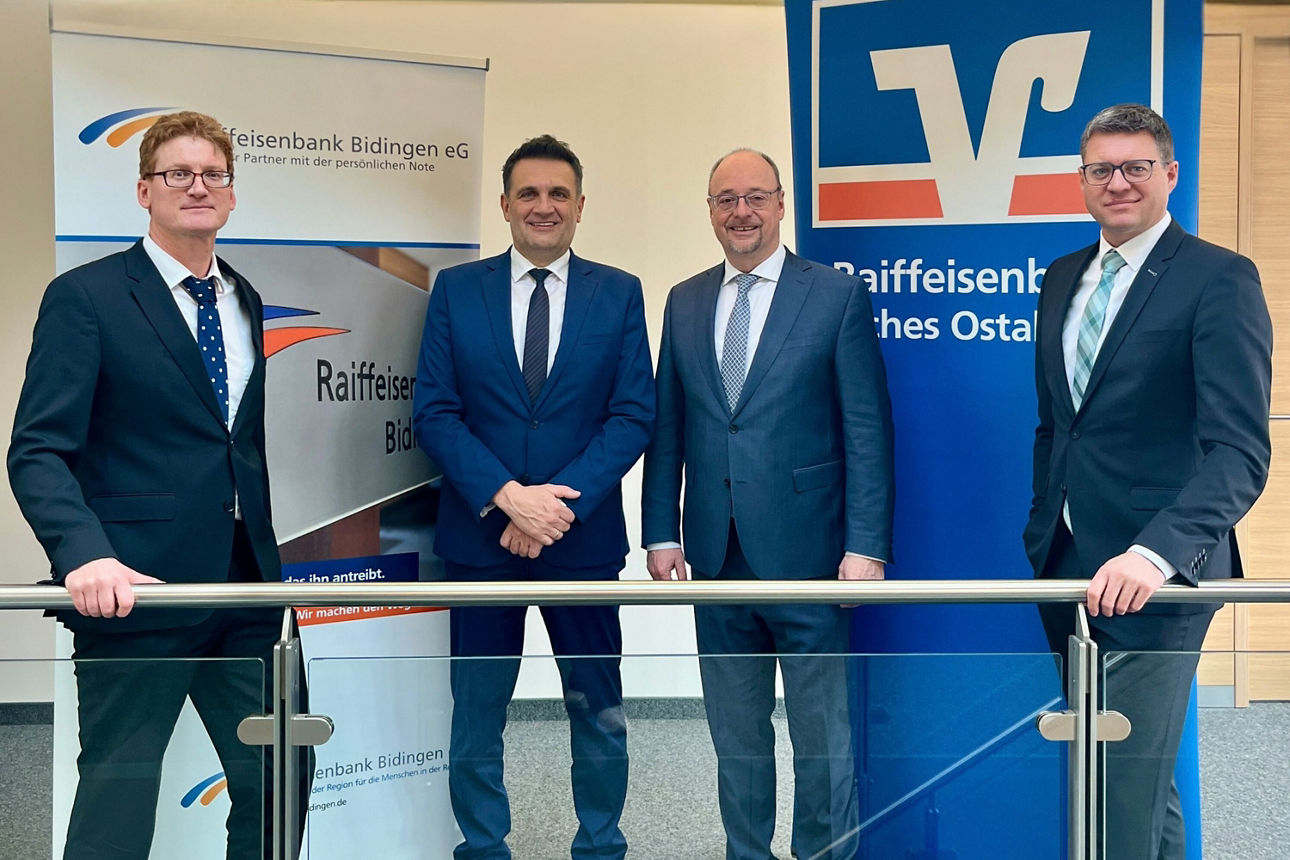 Vier Männer stehen vor einer Stele der Volksbank