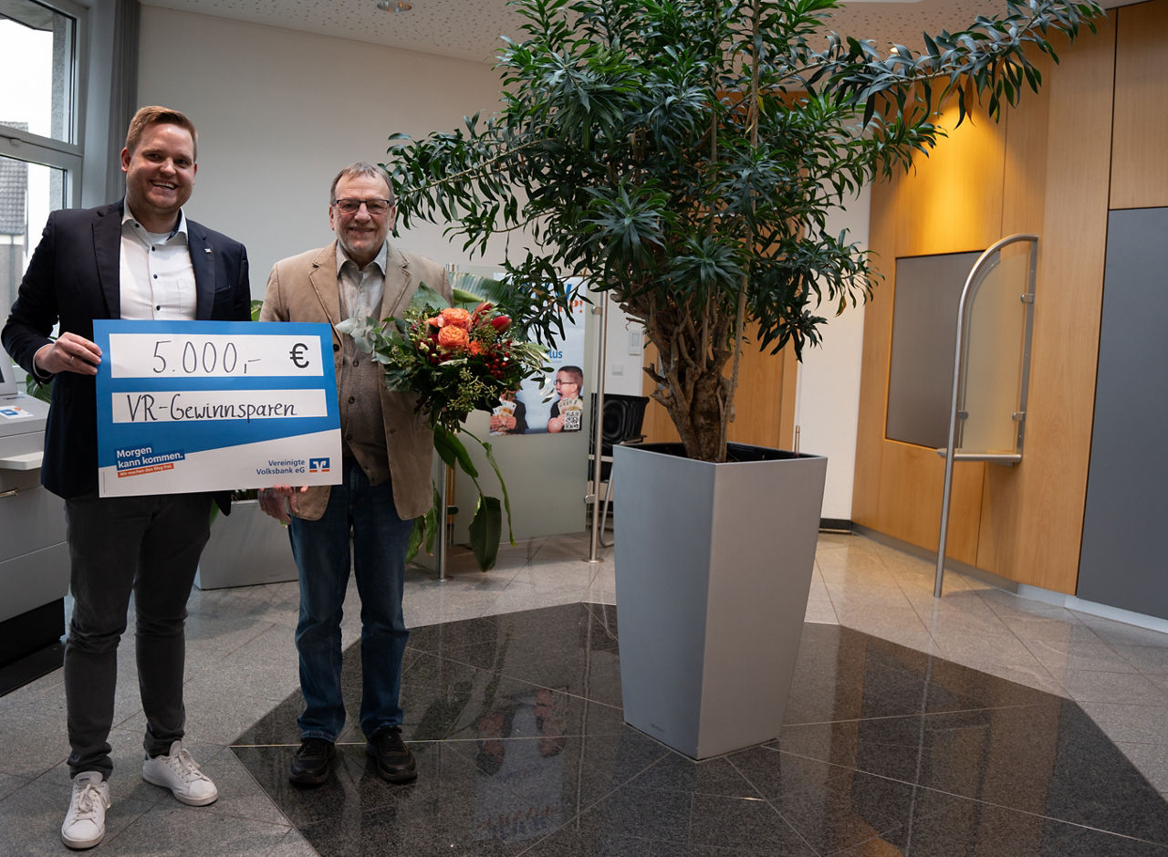 Zwei Männer mit einem Scheck über 5000€